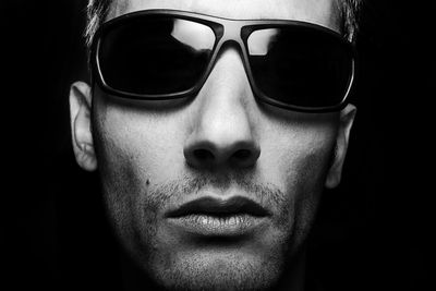 Close-up portrait of adult man against black background