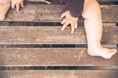 Low section of baby sitting on wooden plank