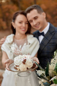 Portrait of smiling couple holding bouquet