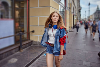 Portrait of young woman standing against wall