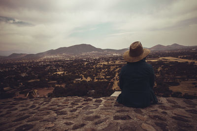 Rear view of woman looking at cityscape against sky