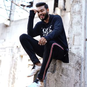 Low angle view of smiling young man sitting on stone wall