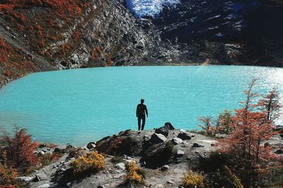 Rear view of man standing on lakeshore