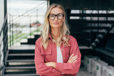 Modern business woman in glasses and a suit stands with her arms crossed person