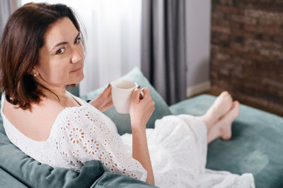 Young woman using mobile phone while sitting on table