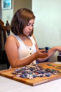 Young girl works on assembling a jigsaw puzzle at home