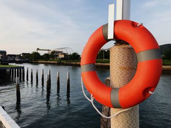 Red wooden post in river against sky
