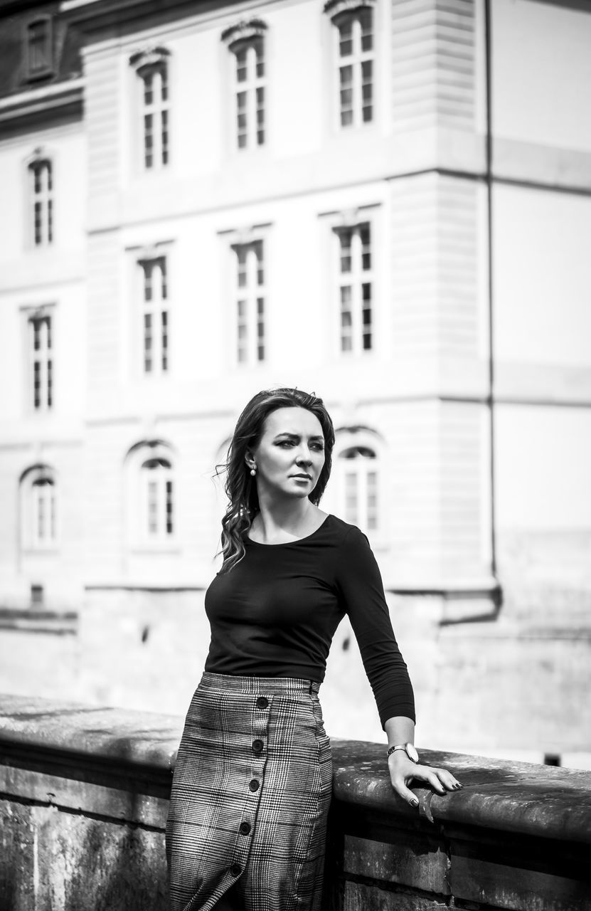 PORTRAIT OF BEAUTIFUL YOUNG WOMAN STANDING AGAINST BUILDING