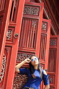 Woman wearing sunglasses while standing by traditional building