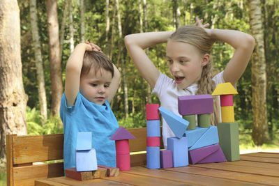 Cute siblings playing with toy blocks outdoors