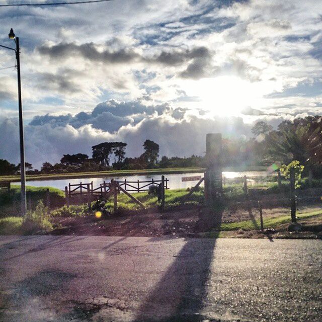 sky, sun, cloud - sky, sunlight, sunbeam, water, tranquil scene, tranquility, nature, beauty in nature, scenics, railing, lens flare, cloud, tree, sunny, mountain, cloudy, river, lake