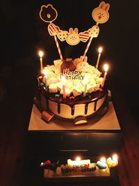 Illuminated tea light candles on birthday cake