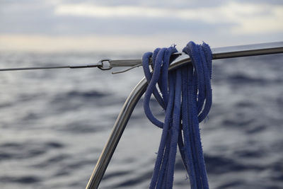 Close-up of rope tied on wooden post against sky