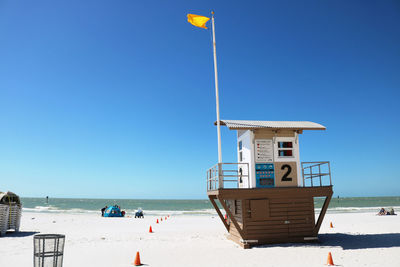 Lifeguard hut on beach against clear blue sky