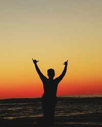 Silhouette woman standing by sea against sky during sunset