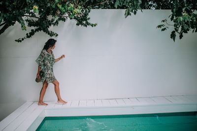 Woman standing by swimming pool against trees