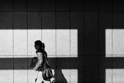 Side view of woman walking against wall