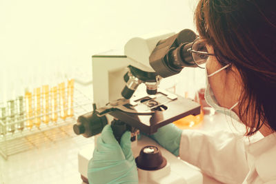 Rear view of woman looking into microscope