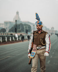 Full length portrait of young man standing against city in background