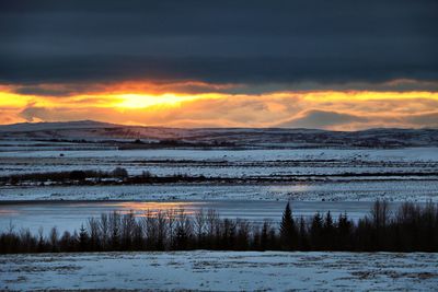 Scenic view of snow covered land against sky during sunset