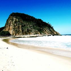 Scenic view of beach against clear blue sky