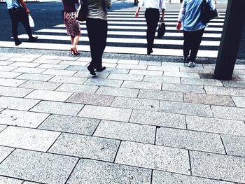 Low section of people walking on zebra crossing