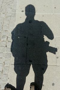 Shadow of man on street during sunny day