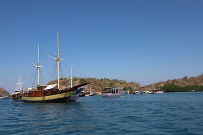 Boats sailing in sea against clear blue sky