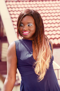 Smiling young woman standing against building