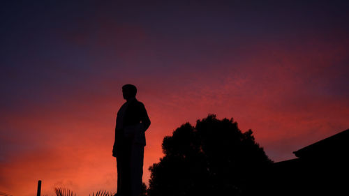 Silhouette man standing against orange sky