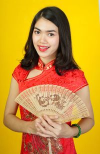 Portrait of smiling young woman against yellow background