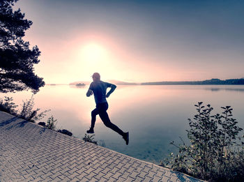 Freeze sportsman in running pose. runner is sprinting along mountain lake within morning mood