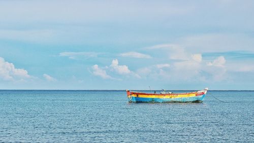 Scenic view of boat in calm sea against cloudy sky