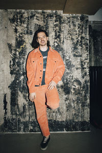 Portrait of young man standing against wall