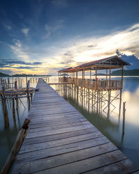 Pier over sea against sky during sunset