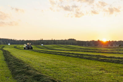 Tractor working in field at sunset