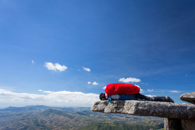 Rear view of man on mountain against blue sky