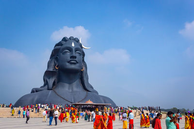 Statue of people against blue sky