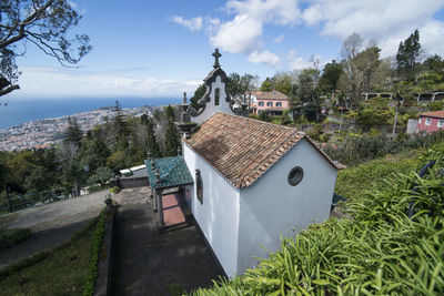 Houses by trees and buildings against sky