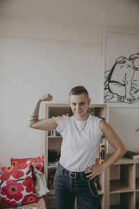 Portrait of young man standing against wall at home