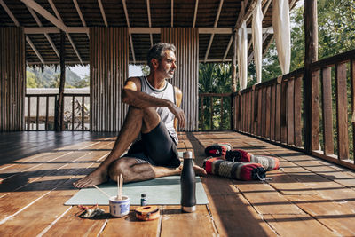 Mature man doing matsyendrasana pose on yoga mat at wellness resort
