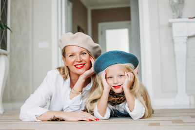 Portrait of happy mother and daughter lying on carpet at home