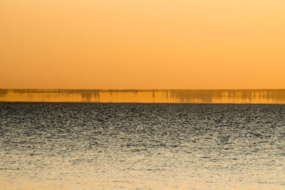 Scenic view of sea against orange sky