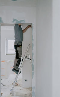 A young caucasian male builder clears a doorway using a crowbar.