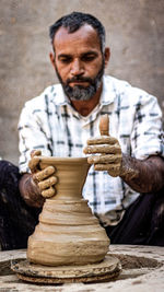 Man making pottery while sitting outdoors