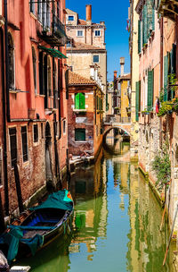 Boats moored in canal amidst city