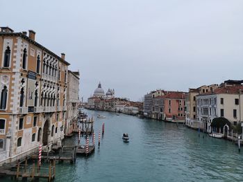 Boats in canal by buildings against sky