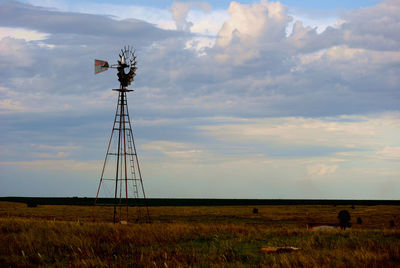 Windmill on field against sky during sunset