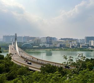 Bridge over river in city against cloudy sky