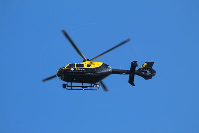 Low angle view of helicopter against clear blue sky